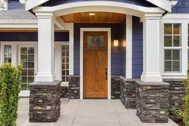 Home Entrance with Stacked Stone Accents and Pillar Supports 