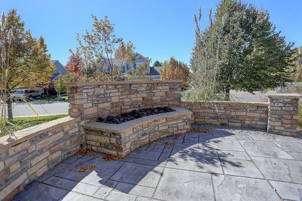 Outdoor built-in stone fire pit with stone wall patio surround