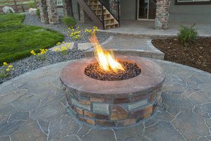 Outdoor build in stone gas fire pit on natural stone patio